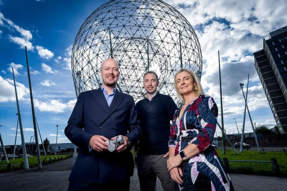 Three members of the Profast Group team in front of the 'balls of the falls' in Belfast