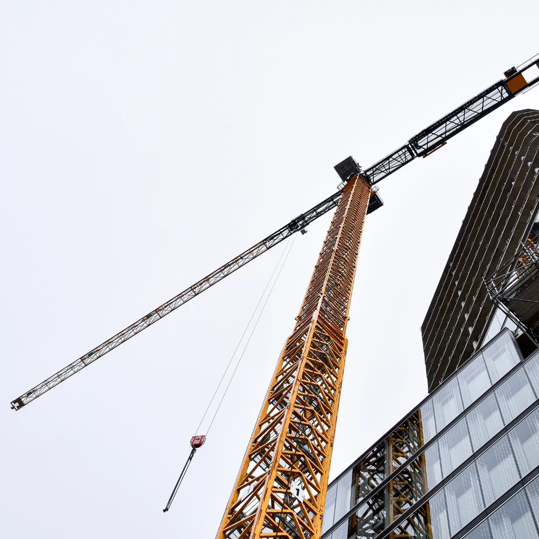 Worms eye view of large yellow crane beside a buiilding